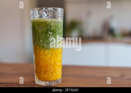 Latte matcha au mangue glacé en couches dans un grand verre sur la table de la cuisine Banque D'Images