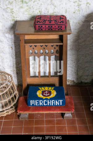 Anglesey, Royaume-Uni - 29 mai 2026 : Un genouillet brodé de la Marine Marchande repose sur un banc en bois à l'intérieur de l'historique église d'Eglwys Llanbadrig près de la baie de Cemaes Banque D'Images