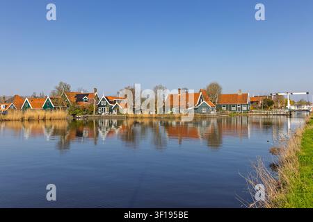 Zaandam, Pays-Bas. Vue panoramique du musée en plein air historique de Zaanse Schans avec des maisons en bois vert traditionnelles et un pont-levis se reflétant dans l'eau Banque D'Images