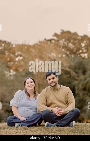 Scène de maternité automnale paisible mettant en scène un couple enceinte assis à l'extérieur, partageant un moment calme et aimant tout en attendant leur future fille Banque D'Images