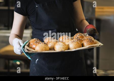 Boulangerie féminine souriante tenant du pain frais Artisan Sourdough dans Bakery Banque D'Images