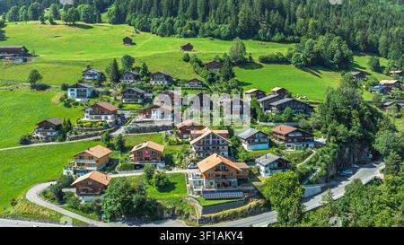 Vue aérienne d'un village suisse pittoresque avec des chalets en bois dans le paysage alpin verdoyant Banque D'Images