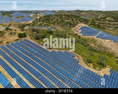 Vue aérienne d'une ferme solaire à grande échelle avec des rangées de panneaux photovoltaïques installés à travers les collines ondulantes de la campagne à Vaqueiros, Faro Dist Banque D'Images