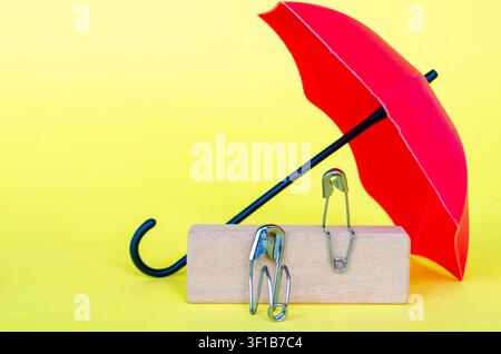 Parapluie rouge couvrant des figurines en forme de broche conseillant ou réconfortant une autre figurine avec un espace personnalisable pour le texte. Banque D'Images