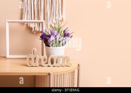 Panneau en bois avec motif de rêve et fleurs de crocus violettes dans un pot blanc sur une table en bois clair avec décoration en macramé, une tenture murale en macramé fournit un fond texturé Banque D'Images