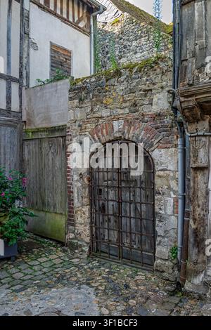 Une arche en pierre historique mène à une charmante ruelle européenne. Les textures patinées des matériaux de construction évoquent un sentiment d'éternité et i Banque D'Images
