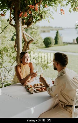 Un couple savoure un délicieux repas ensemble sous une canopée de fleurs. Banque D'Images