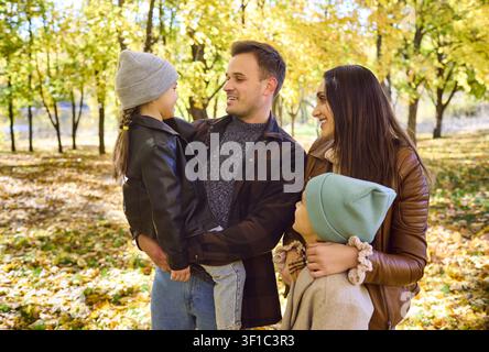 Parents souriants avec deux enfants créant des liens dans un parc ensoleillé d'automne, portrait Banque D'Images