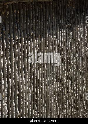 Allemagne 2026 Vue rapprochée d'un mur de béton gris usé avec des rainures verticales répétitives, une surface rugueuse, des veines minérales pâles et une ambiance industrielle atténuée Banque D'Images