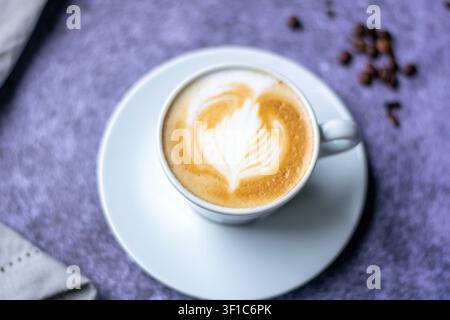 Close-up d'un cappuccino avec un art latte en forme de cœur dans une tasse en céramique blanche. Banque D'Images