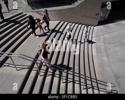 Les acheteurs et les navetteurs descendent un large escalier extérieur menant aux places d'entreprises modernes du domaine de Broadgate dans la City de Londres, au Royaume-Uni, vêtus de vêtements légers d'été pendant une période de temps chaud Banque D'Images
