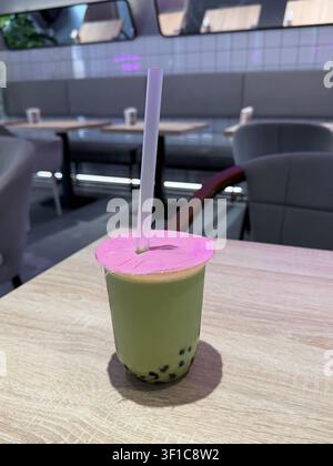 Thé à bulles au matcha avec perles de tapioca servi sur une table de café dans un intérieur moderne avec un flou d'arrière-plan doux. Culture café, tendance alimentaire, style de vie Banque D'Images