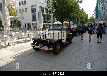 Pforzheim, Allemagne - 10 juillet 2019 : Une voiture de collection classique à toit ouvert est garée à côté des tables d’extérieur d’un café sur une route piétonne lumineuse de la ville, tandis que des gens se promènent Banque D'Images