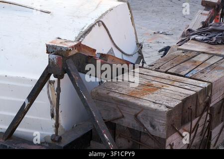 Coque de bateau reposant à l'envers sur un support métallique robuste et de gros blocs de bois, mettant en valeur les matériaux patinés et la préparation pour la maintenance Banque D'Images