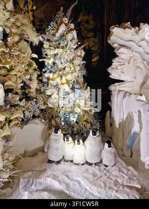 Maincy, France – 11 décembre 2025 : Famille de pingouins en peluche sur de la neige factice et des arbres d’hiver en arrière-plan. Décoration magique de Noël à l’intérieur du h Banque D'Images