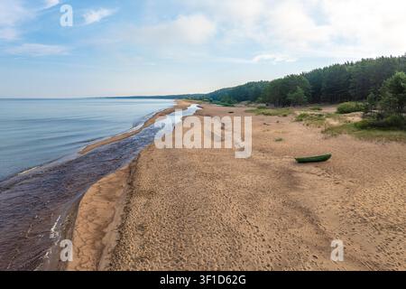 Vue aérienne de l'estuaire sinueux de la rivière Pēterupe avec un petit bateau de pêche sur la plage à Saulkrasti, Lettonie Banque D'Images