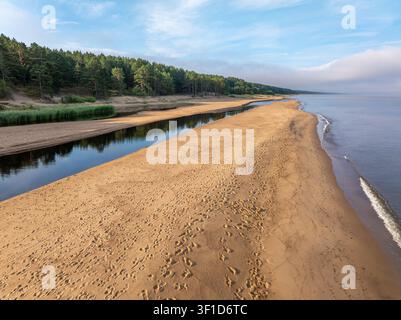 Estuaire de la rivière Peterupe rencontrant la mer Baltique près de Saulkrasti, Lettonie vu du dessus au lever du soleil Banque D'Images