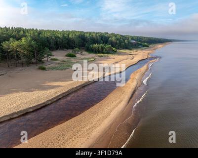 Vue aérienne de l'estuaire de la rivière Peterupe rencontrant la mer Baltique au lever du soleil près de Saulkrasti, Lettonie Banque D'Images