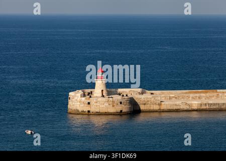Le phare de Ricasoli surplombe les eaux bleues et calmes à l'entrée du Grand Harbour, Kalkara, Malte Banque D'Images