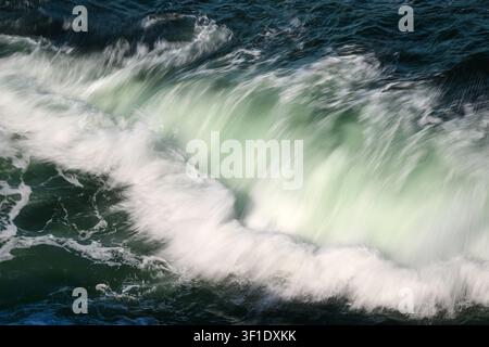 Détail en gros plan d'une vague de l'océan qui s'écrase, créant un bord d'écume blanc avec une couleur verte dans la vague Banque D'Images