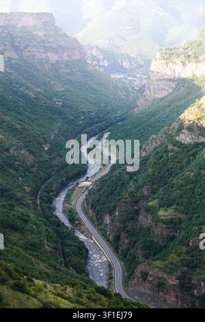 Une rivière sinueuse et une route pavée parallèle serpentent au fond d'un canyon profond et boisé bordé de hautes falaises. Rivière Debed, Arménie Banque D'Images