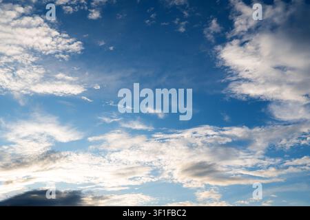 Beau ciel bleu éclatant rempli de doux nuages cirrus blancs et gris lors d'une journée ensoleillée, texture naturelle. Banque D'Images