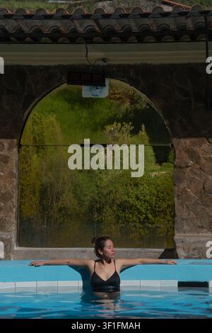 Femme se détendant dans une piscine d'eau chaude en plein air. Banque D'Images