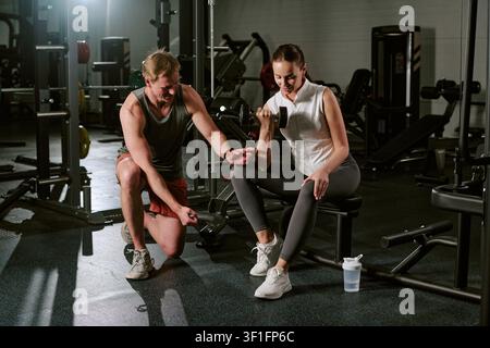 Jeune femme s'entraînant avec un entraîneur personnel dans une salle de sport pour la forme physique Banque D'Images