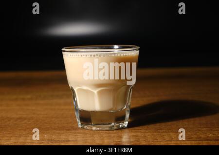 Close-up de lattes fraîchement préparés dans des verres à côté d'une cafetière noire sur une table en bois Banque D'Images