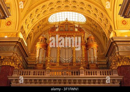 Orgue massif et orné en or sur la balustrade sous une arche décorée à l'intérieur de la basilique Saint-Étienne à Budapest. Banque D'Images