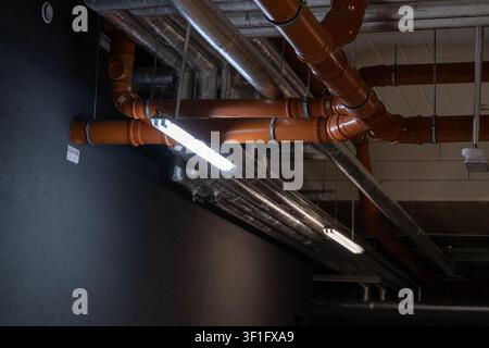 Systèmes d'ingénierie montés au plafond dans un bâtiment commercial comprenant des conduits de ventilation, des tuyaux utilitaires et un éclairage industriel. L'image représente Banque D'Images