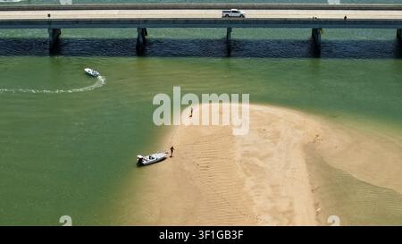 Vue aérienne du bras de mer de Matanzas avec un pont enjambant l'eau, un petit bateau ancré sur un banc de sable et des gens marchant sur la plage à St. Johns C Banque D'Images