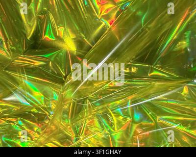 Matériau en feuille dorée plissé reflétant des couleurs iridescentes vibrantes. Surface texturée et brillante offrant un fond abstrait pour le design, l'artisanat ou la décoration de fête Banque D'Images