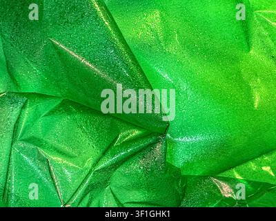 Fond abstrait présentant une texture de matériau vert brillant avec de fines gouttelettes d'eau. La surface texturée crée de la profondeur et de l'intérêt visuel, adaptée pour Banque D'Images