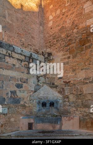 Fontaine historique en pierre avec deux becs en forme de masques métalliques intégrés dans un mur de maçonnerie érodé à Onda, Castellon, Castello, Communauté valencienne, Espagne. UE. Banque D'Images