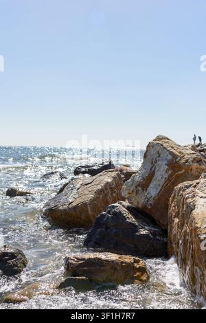 Civitavecchia, Italie - 12 mars 2022. Prise de vue verticale de gros rochers texturés et de gros blocs sur une côte ensoleillée avec des vagues de mer, des reflets de soleil sur l'eau et d Banque D'Images