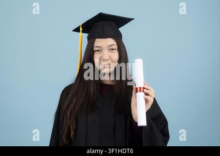 Jeune diplômée fière tenant son diplôme universitaire sous forme de parchemin Banque D'Images