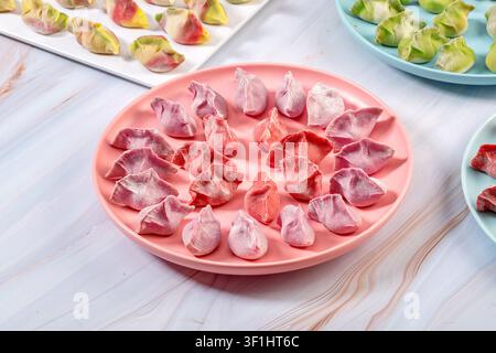 Dumplings de légumes colorés crus et frais sur des assiettes, Jiaozi chinois congelés Banque D'Images