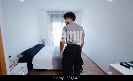 Jeune homme s'habillant dans la chambre avant le travail à distance Banque D'Images