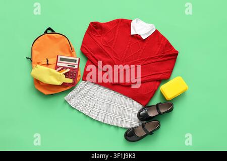Uniforme scolaire avec sac à dos, calculatrice et boîte à lunch pour la saison de la rentrée sur fond vert Banque D'Images