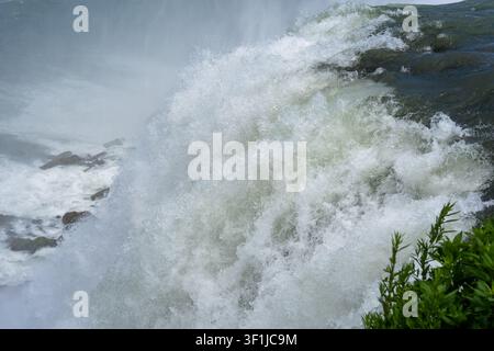 Un plan horizontal en gros plan se concentrant sur l'eau blanche puissante et rugissante ainsi que sur l'écume épaisse au sommet des chutes du Niagara. Une épaisse brume et des gouttelettes d'eau s'élèvent Banque D'Images