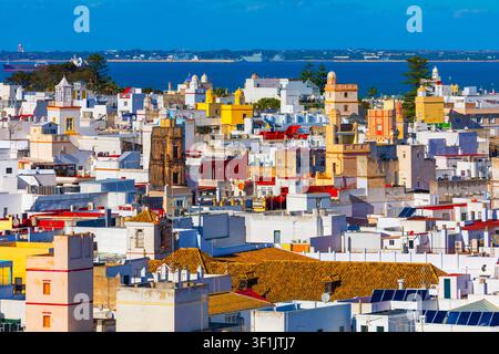 Une vue aérienne ensoleillée capture la vieille ville historique de Cadix, en Espagne. Des postes de guet marchands aux couleurs vives et des bâtiments blancs s'étendent vers la baie bleue Banque D'Images