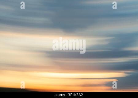 Une image abstraite ICM montrant un mouvement intentionnel de la caméra avec une lumière fluide dans les couleurs du coucher de soleil, bleu et orange, avec une texture douce. Banque D'Images