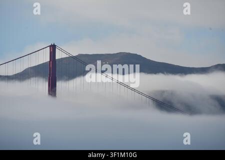 Tour du Golden Gate Bridge s'élevant au-dessus d'un épais brouillard blanc sur la baie de San Francisco, Californie, États-Unis Banque D'Images
