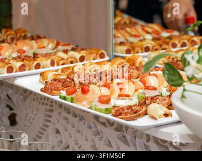 Canapés salés variés et mini-sandwichs disposés sur des plateaux de traiteur lors d'une réception Banque D'Images
