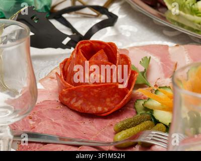 Rose décorative de salami avec assortiment de charcuterie et garniture de légumes sur une assiette de charcuterie Banque D'Images