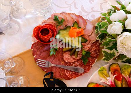 Plateau de charcuterie décoratif avec divers charcuteries et garniture de légumes lors d'une réception Banque D'Images