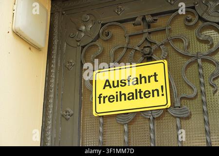 Berlin, Allemagne - 16 juillet 2026 : Panneau jaune « Gardez la voie libre » fixé sur une porte en fer forgé Art Nouveau décorative dans la Zimmermannstraße, Steglitz. Banque D'Images