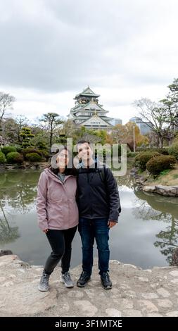 Un couple profite d'un moment de sérénité au Jardin Japonais du Château d'Osaka, surplombant la zone principale du palais par une journée tranquille à Osaka, au Japon. La scène Banque D'Images