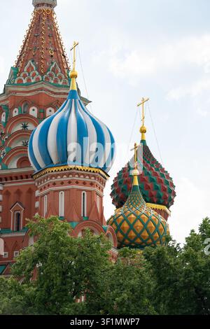 Vue historique en gros plan des dômes de la cathédrale Saint-Basile à Moscou, en Russie, avec des tours en forme d'oignon colorées s'élevant au-dessus des arbres verts sous un ciel pâle Banque D'Images